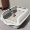 Modern open cat litter box with scooper and clean cat litter in a tidy room