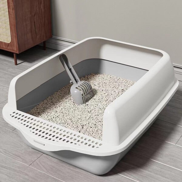 Modern open cat litter box with scooper and clean cat litter in a tidy room