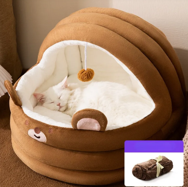 White cat sleeping in a cozy brown bear-shaped cat bed with soft plush interior.