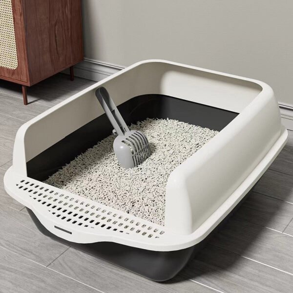 Modern cat litter box with scoop and clumping litter on a gray tiled floor