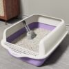 Large purple and white cat litter box with scoop, filled with clean cat litter, on tiled floor