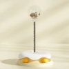 Interactive cat toy with treat dispenser on spring, egg-shaped base, cream background
