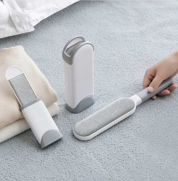 Reusable cat hair remover lint brush set on light carpet with clothing