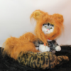 Cat wearing a fluffy lion costume, sitting on a faux fur surface.