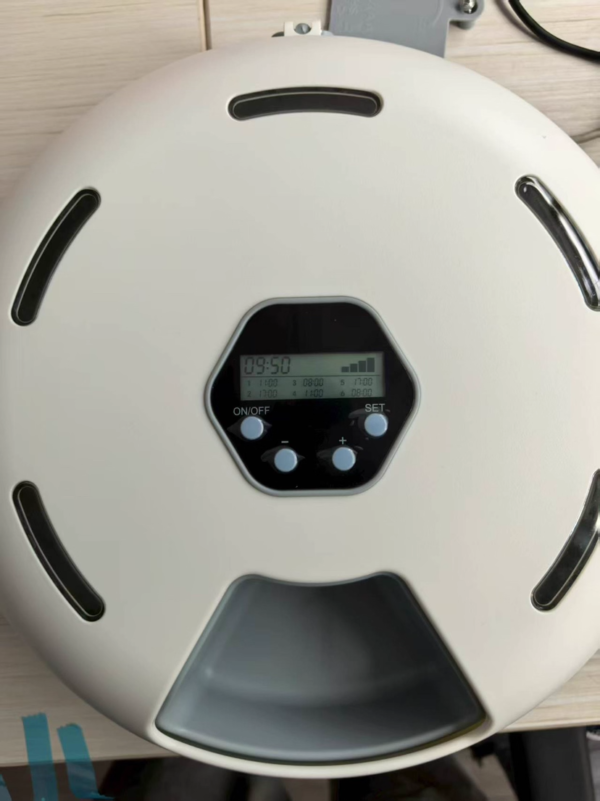 e46eab275547014fd988271396a67a98 Automatic cat feeder with digital display and multiple timer settings on wooden surface