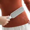 Reusable lint remover brush cleaning pet hair from orange sweater